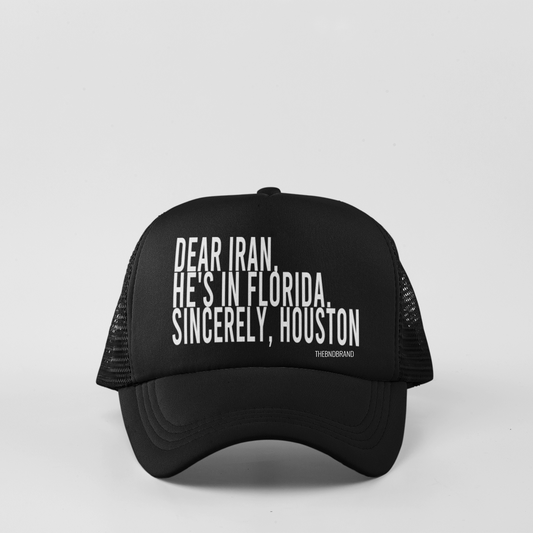 Black trucker hat with white text on a light gray background